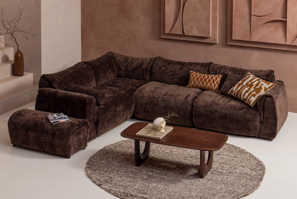 Donkerbruine Baggy chenille bank met Frequent salontafel, kussens, hocker en een sfeervol tapijt met accessoires.