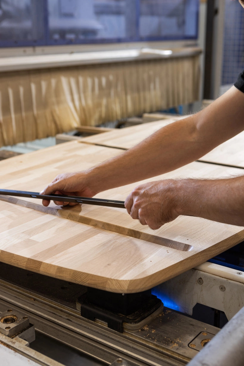 Productiemedewerker aan het werk in de fabriek, bezig met het bevestigen van onderdelen onder een Tablo tafel