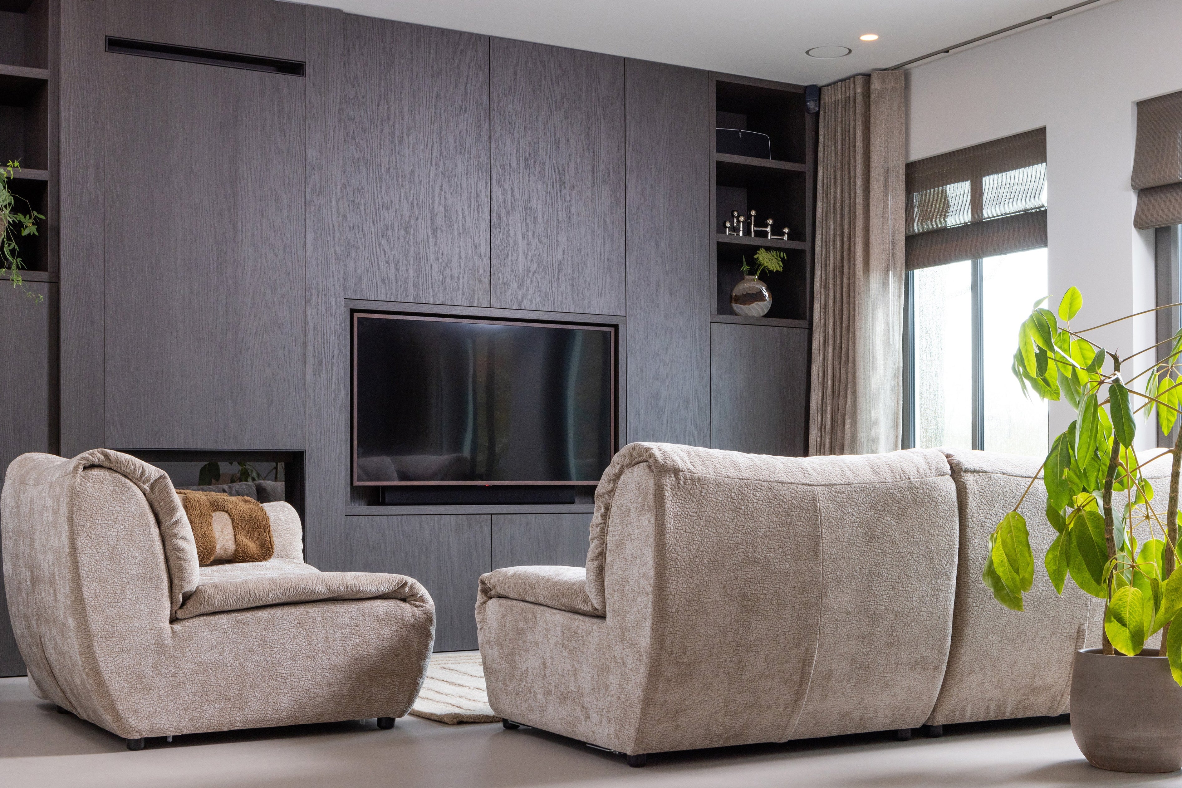 Baggy modulaire bankenserie in een zithoekopstelling, geplaatst voor een zwarte wandkast met tv en decoratieve items.