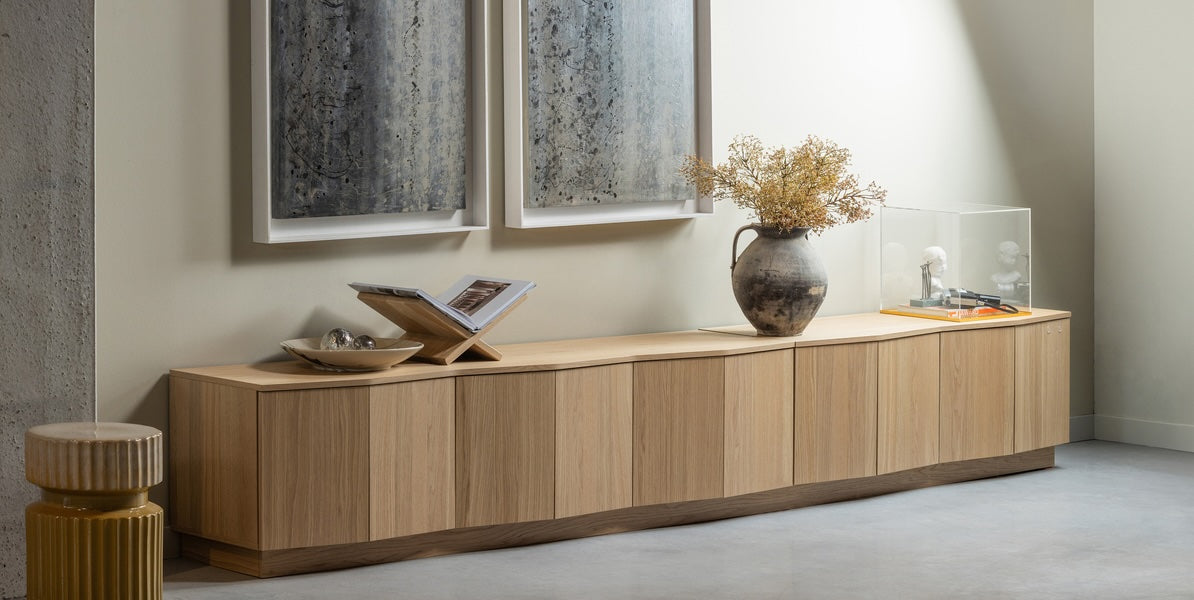 Sfeervol ingerichte ruimte met Zuma tv-meubel en accessoires, waaronder de Geer bijzettafel, verlicht door bovenlicht en afgewerkt met minimalistische schilderijen