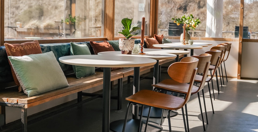WOOOD Tablo bistro tafelpoot in een warme, gezellige restaurantsetting met stoelen eromheen.