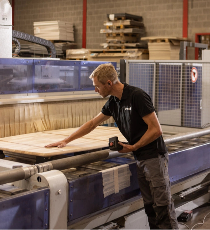 Medewerker in de WOOOD-fabriek bezig met het maken van houten meubelproducten in een industriële omgeving